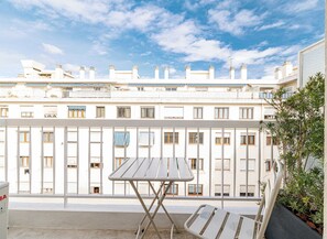 A balcony with a metal table and chairs, overlooking a row of white buildings with multiple windows and balconies. - Mamabaldi Apartment – Elegance, tranquility and views from the top of Nice (Nice)