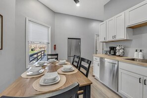 A modern kitchen with white cabinets, a stainless steel refrigerator, and a dining area with a wooden table set for four. - Cleveland Clinic | Recliner | Relaxing | 3 Bedroom (Cleveland)
