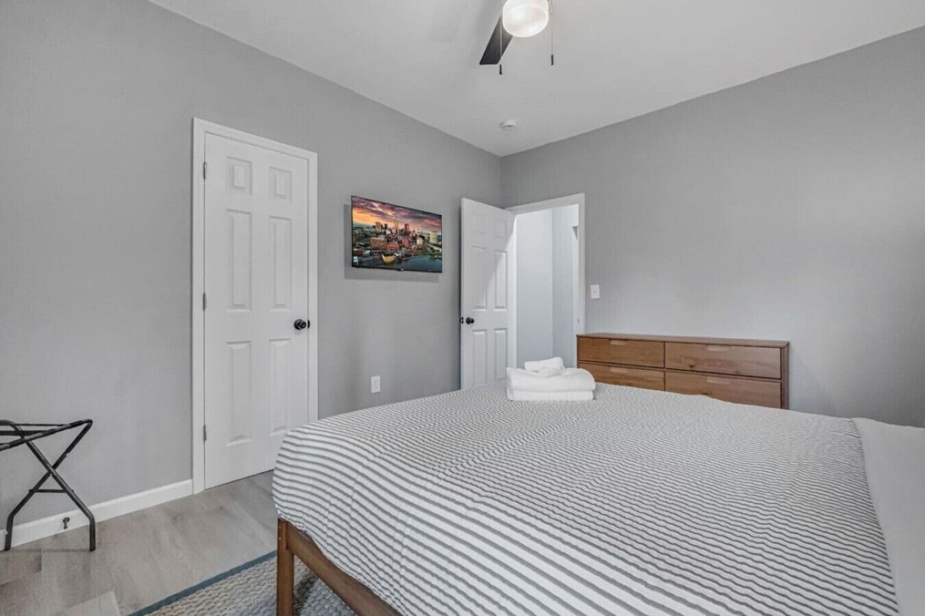 Un dormitorio con cama, cómoda, puerta y un cuadro en la pared.
