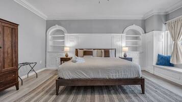 A bedroom with a large bed, two bedside tables with lamps, a wooden wardrobe, and a window with curtains.
