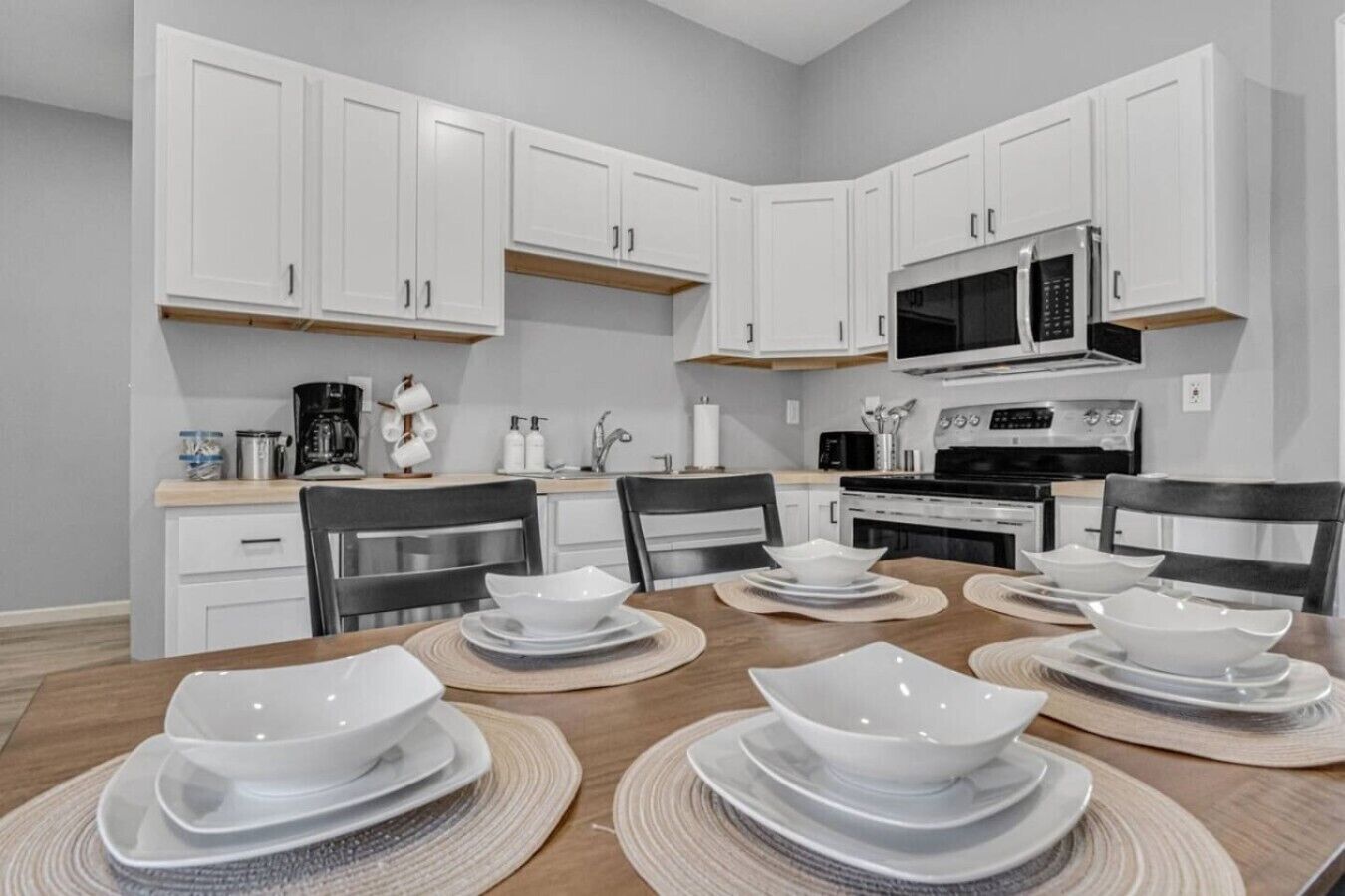 A modern kitchen with white cabinets, a microwave, and a stove.