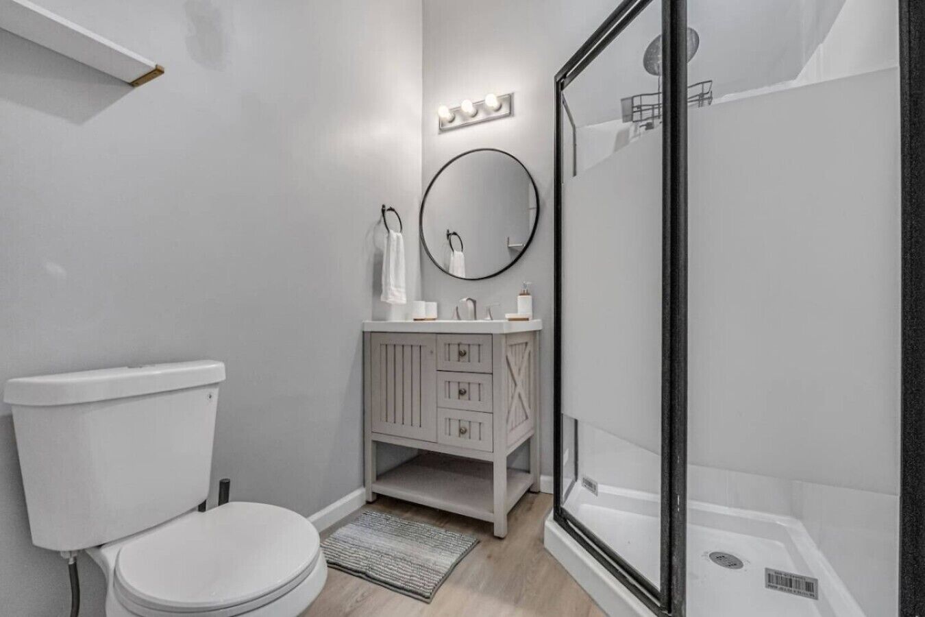 A modern bathroom with a toilet, vanity, and shower.