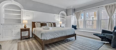 Une chambre avec un grand lit, des étagères intégrées, une fenêtre avec des rideaux et un ventilateur de plafond.