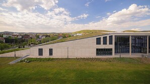 Un bâtiment moderne doté d’un toit en pente, de grandes fenêtres et d’une zone pavée à l’avant.