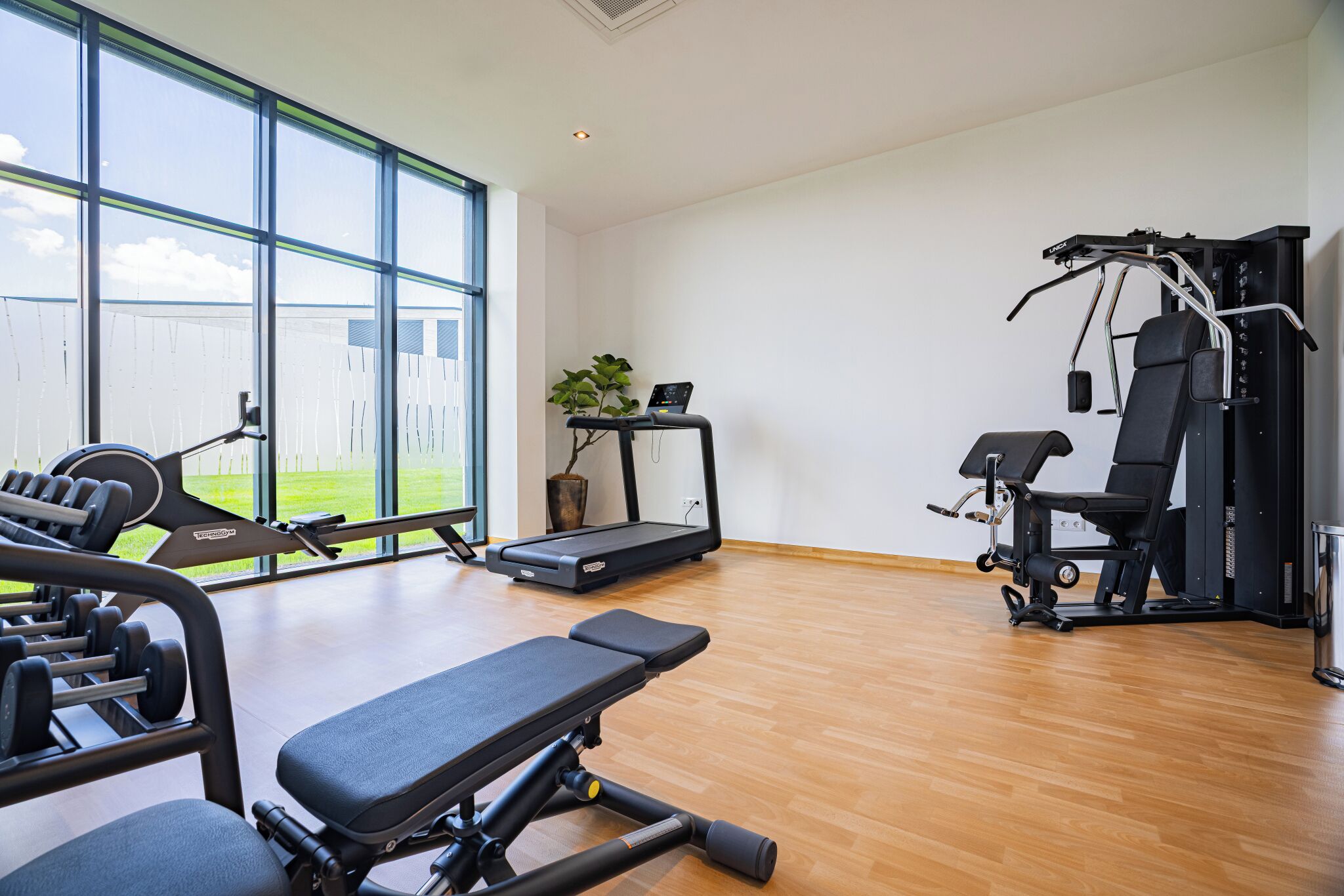 A gym with exercise equipment, a treadmill, and a bench.