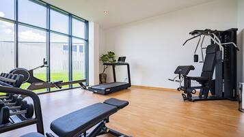A gym with exercise equipment, a treadmill, and a bench.