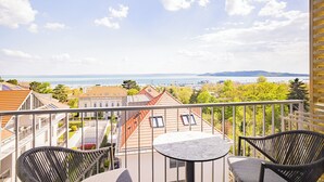 Un balcon avec une table et des chaises, donnant sur une marina et sur une étendue d’eau.