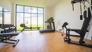 A modern gym with various exercise equipment, large windows, and a wooden floor. - Montello Hotel (Balatonfüred)