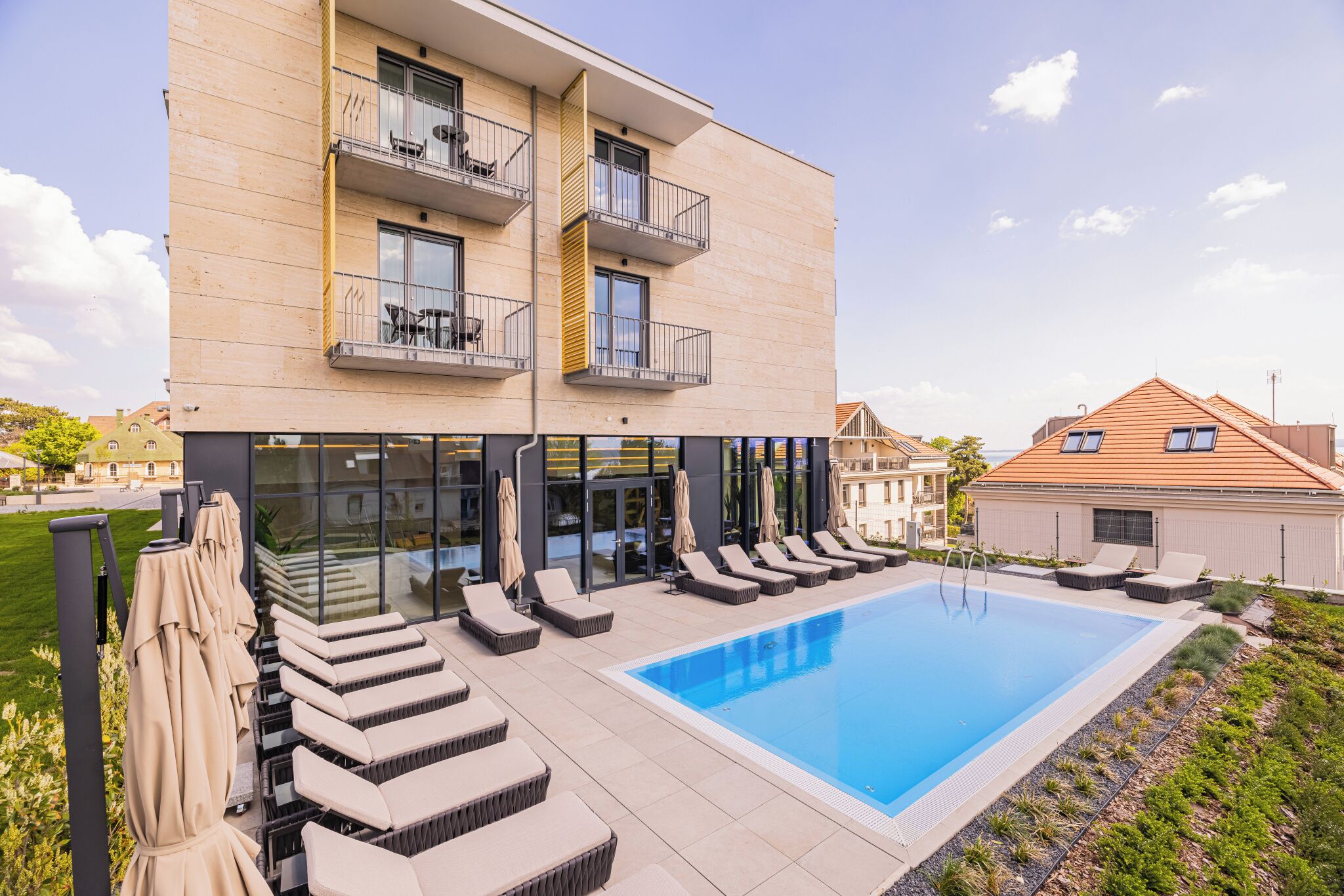 Un edificio moderno con piscina, asientos exteriores y balcón.