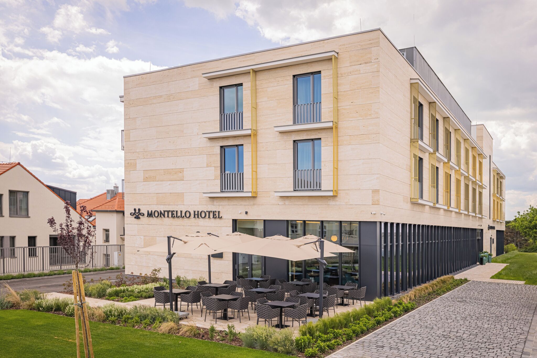 A hotel with a modern facade, outdoor seating area, and a clear sky.