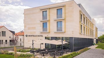 A hotel with a modern facade, outdoor seating area, and a clear sky.