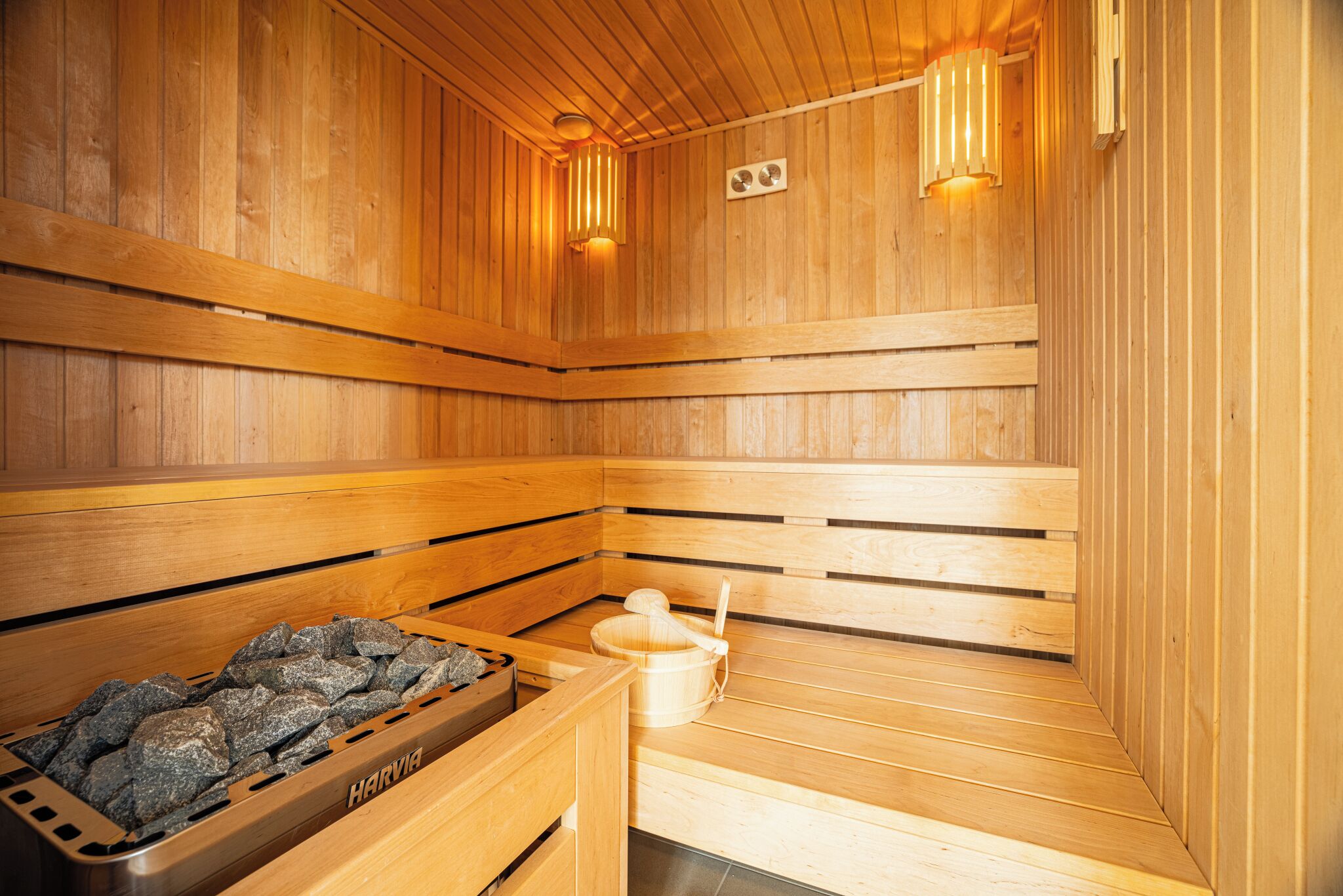 Een sauna met houten banken, een stenen kuip en een houten emmer.