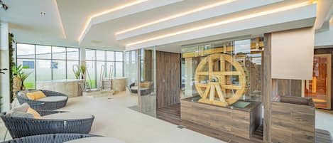 Un espacio interior amplio con mobiliario moderno, una gran estructura circular de madera y un panel de vidrio.