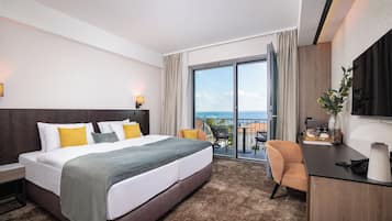 Habitación de hotel con cama, escritorio, silla y vista al mar.