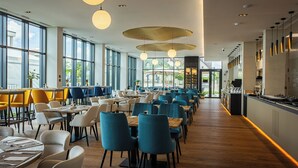 A spacious restaurant with high ceilings, large windows, and a variety of seating arrangements. - Montello Hotel (Balatonfüred)