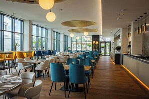 A spacious restaurant with high ceilings, large windows, and a variety of seating arrangements.