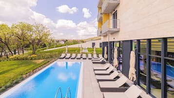 Un bâtiment moderne doté d’une piscine, d’un espace extérieur aménagé et offrant une vue sur le paysage environnant.