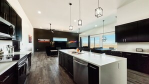 A modern kitchen with a central island, dark cabinetry, and pendant lighting. - Spacious 4-bedroom Lake Powell house close to Lone Rock - Gorgeous Views! (Page)
