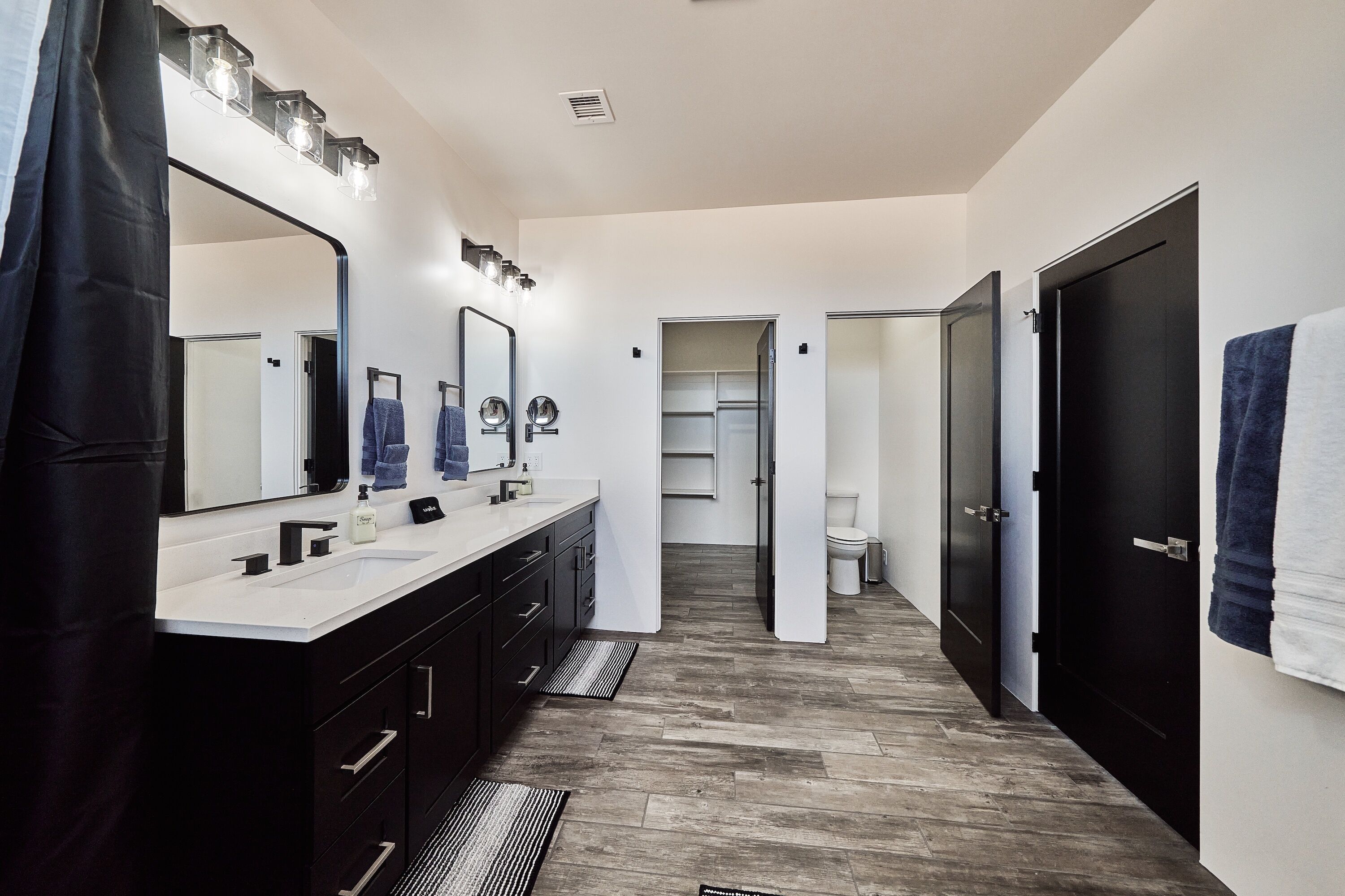 A modern bathroom with a double vanity, a large mirror, and a shower area.