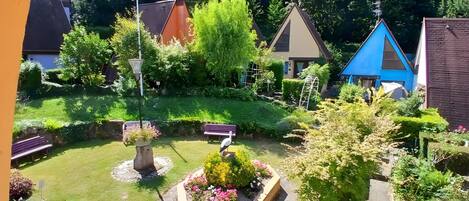 A garden with a bench, a bird feeder, and a flower bed.