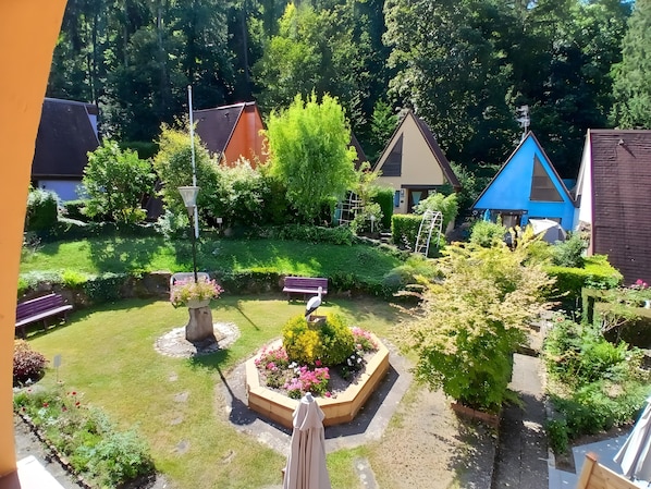 A garden with a bench, a bird feeder, and a flower bed.