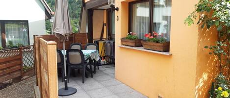 An outdoor patio with a table and chairs, a wooden fence, and flower planters on the wall.