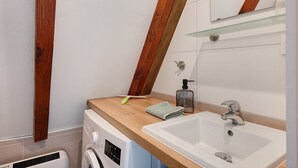 Une petite salle de bain avec un meuble-lavabo en bois, un lave-linge et un évier.