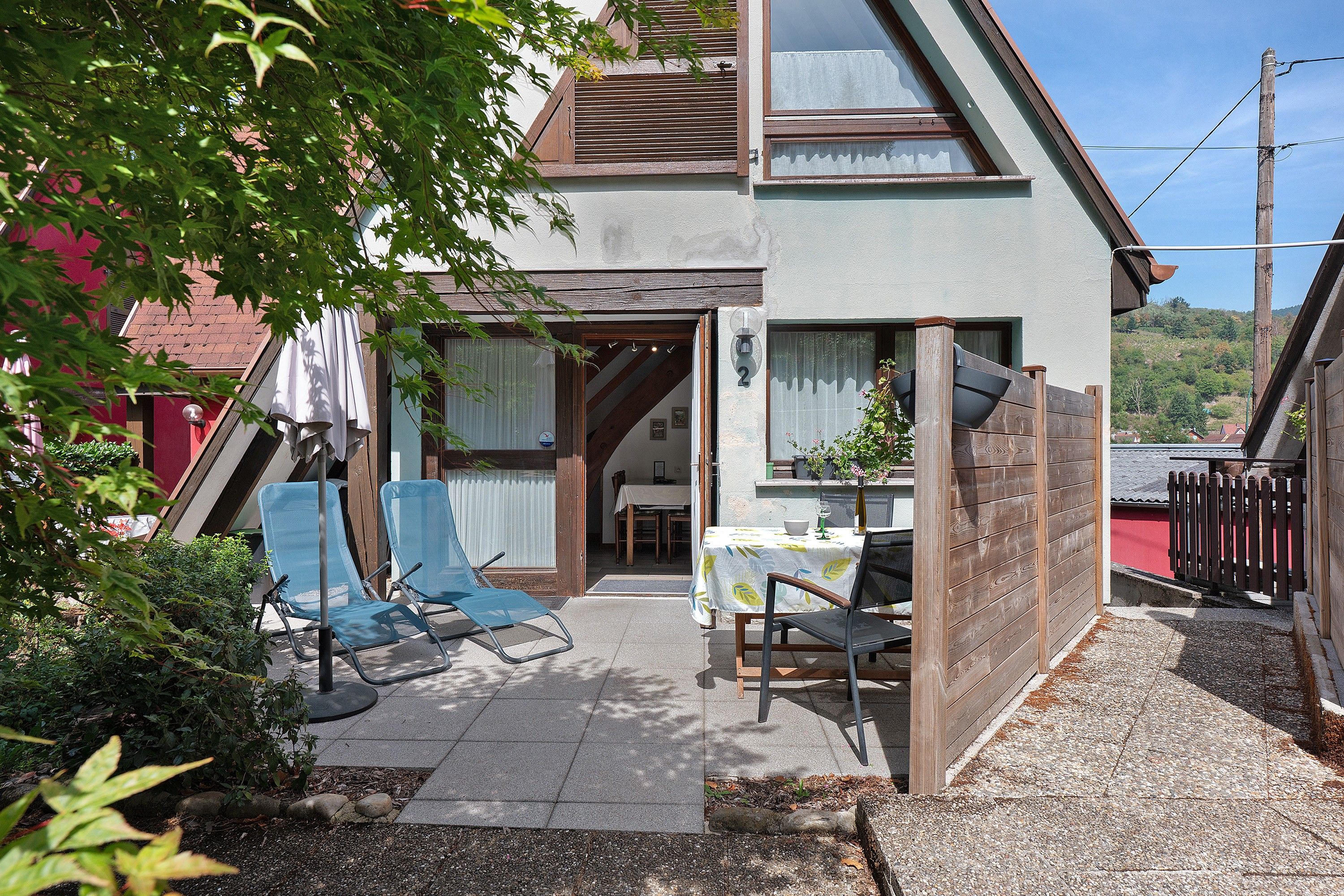 A two-story building with a patio area featuring outdoor seating and a table.