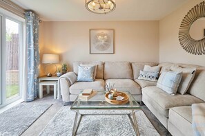 A living room with a sofa, a glass coffee table, and a lamp. - Host & Stay | Stratton Close (Brotton)