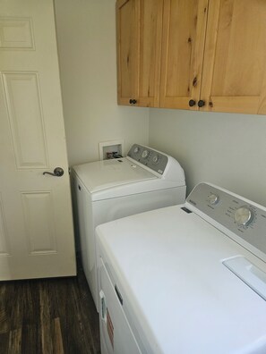A laundry room with two stacked washers and dryers, wooden cabinets above, and a white door. - Big Skies, Big Fun, Room for Everyone! 
6 bedrooms, 3 full Baths, 11 Beds! (Star Valley Ranch)