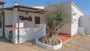 A house with a white exterior, a red roof, and a large tree in the front yard. - Rural House "Los Naranjo" with Mountain Views, Pool, and Barbecue (Jerez de los Caballeros)