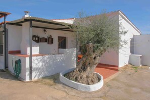 A house with a white exterior, a red roof, and a large tree in the front yard. - Rural House "Los Naranjo" with Mountain Views, Pool, and Barbecue (Jerez de los Caballeros)
