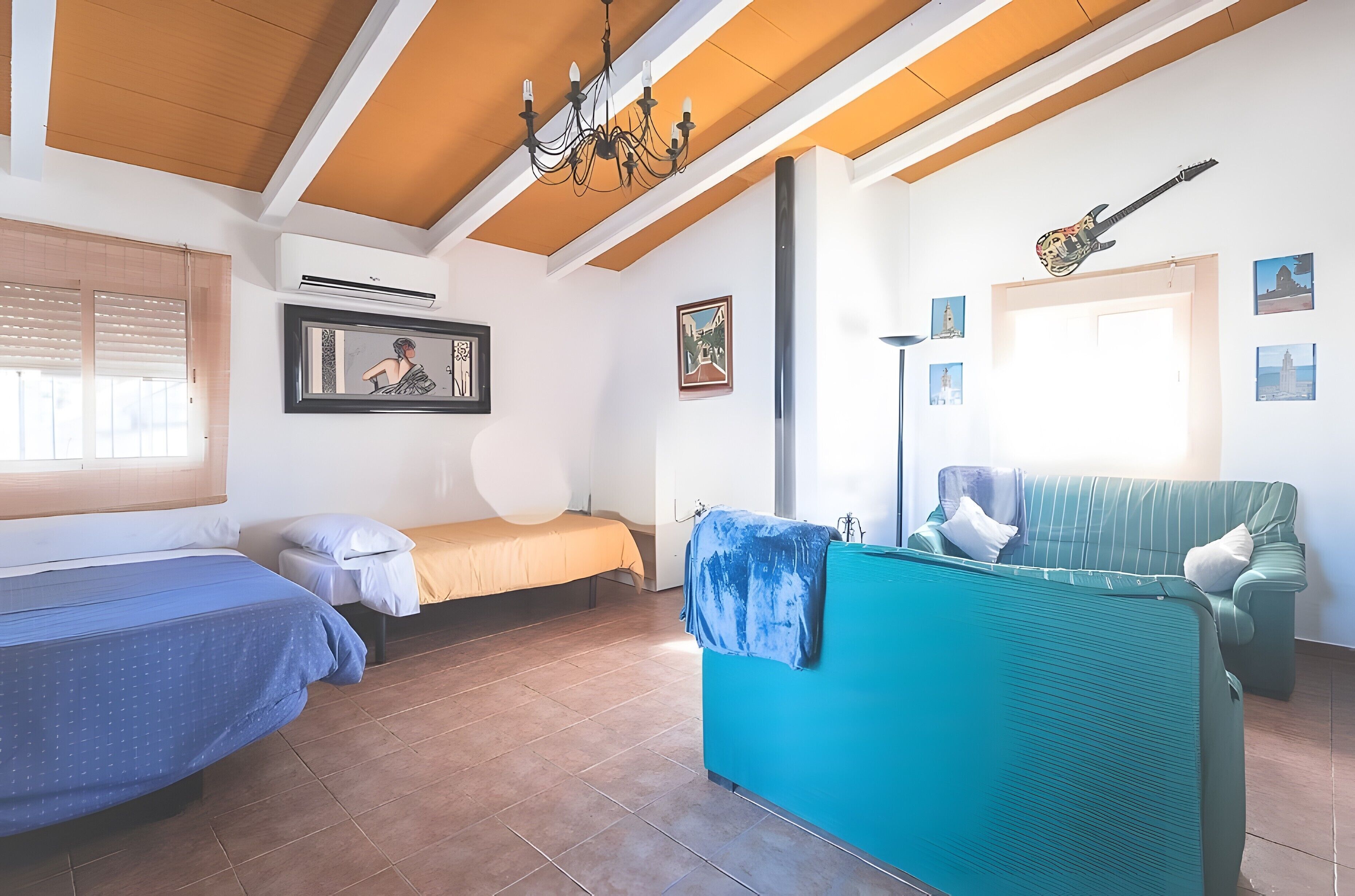 Una habitación con dos camas, un sofá, una lámpara de araña y cuadros en las paredes.