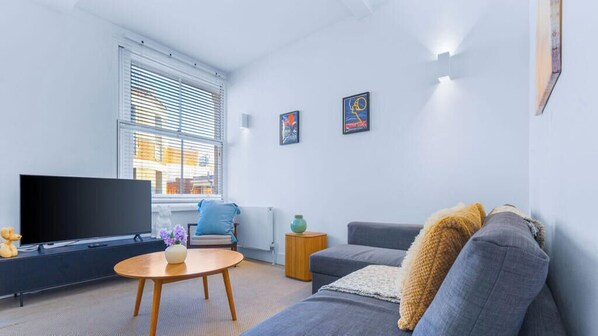 Ein modernes Wohnzimmer mit Flachbildfernseher, einer Couch, einem Couchtisch und Kunstwerken an den Wänden.