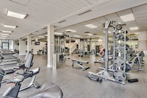 Uma academia com diversos equipamentos de exercício, esteiras e aparelhos de musculação.
