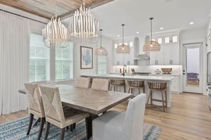 A modern kitchen with white cabinetry, a central island, and pendant lighting. - Luxury Coastal Retreat in Miramar Beach (Miramar Beach)