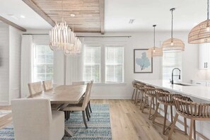 Una cocina moderna con una isla de madera, luces colgantes y un comedor con una mesa grande y sillas.