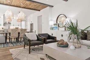 A modern living room with a sofa, a coffee table, and a dining area with chairs and a table. - Luxury Coastal Retreat in Miramar Beach (Miramar Beach)