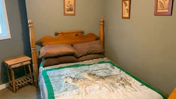 Un dormitorio con una cama de madera, una colcha con diseño de lobo y cuadros en la pared.