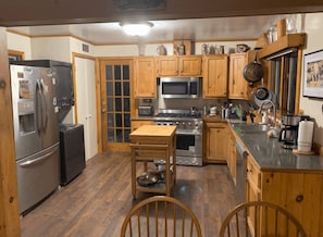 A kitchen with wooden cabinets, a refrigerator, a microwave, a stove, and a sink.