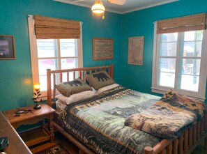 A bedroom with a wooden bed, a nightstand, a lamp, and a window with a view.