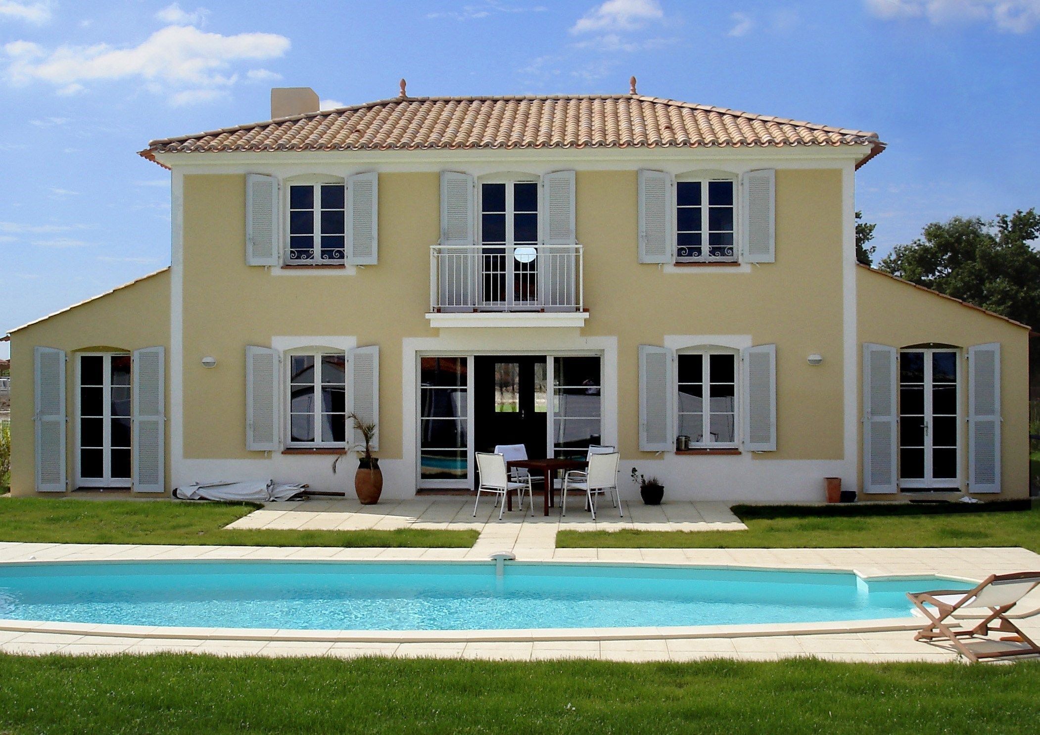 Una casa de dos pisos con una piscina delantera.