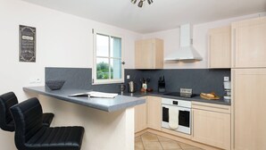 Una cucina moderna con angolo bar, forno integrato e finestra che lascia entrare luce naturale.