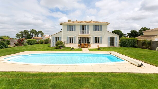 Una casa a due piani con piscina sul davanti.