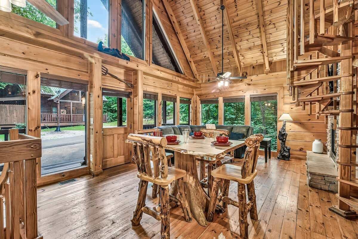 Un intérieur rustique en bois, avec une table à manger, des chaises et un ventilateur de plafond.