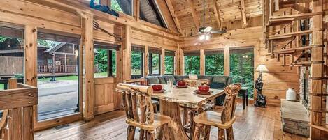 A rustic wooden interior with a dining table, chairs, and a ceiling fan.