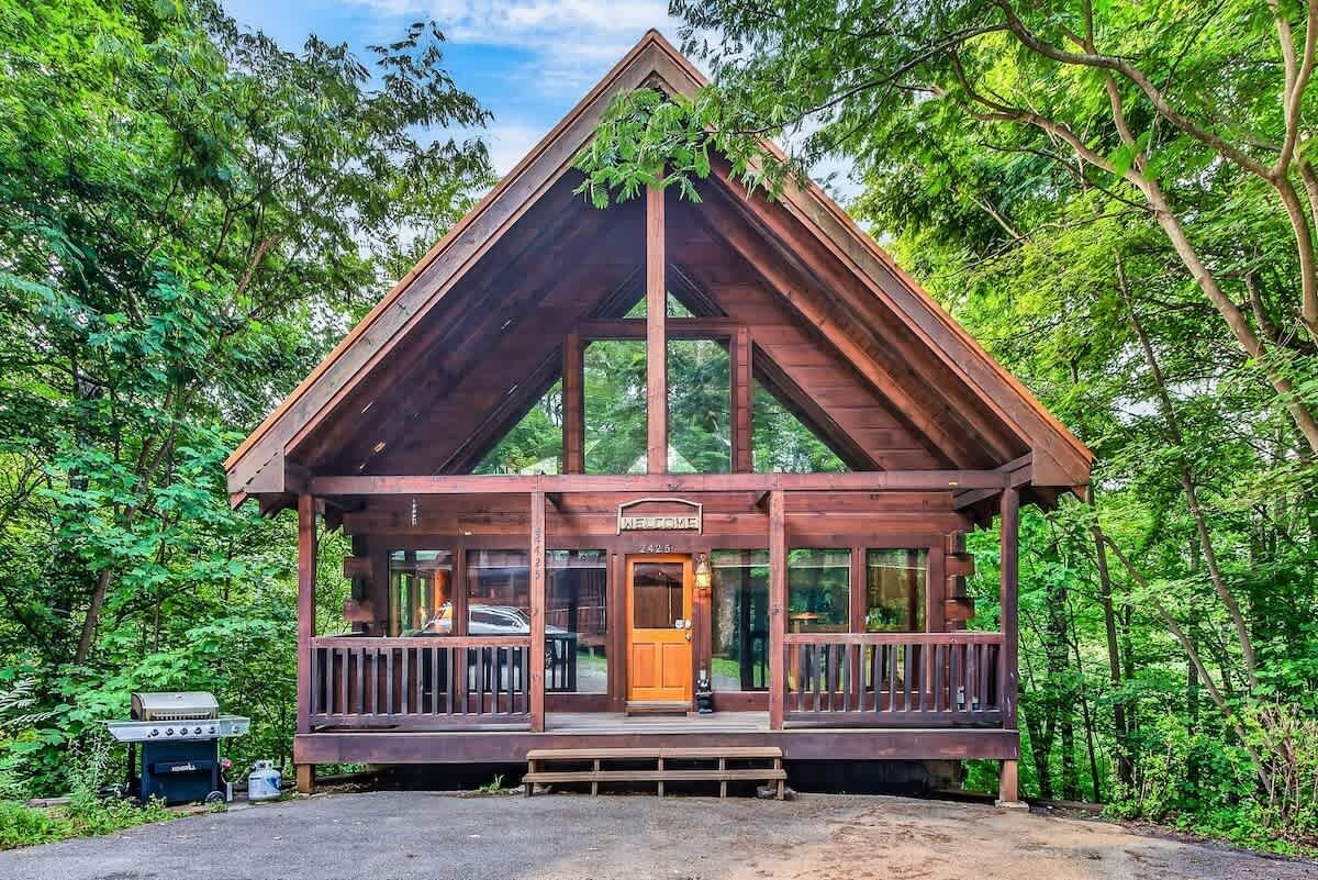 A wooden cabin with a porch, a door, and a sign that reads 'WELCOME'.
