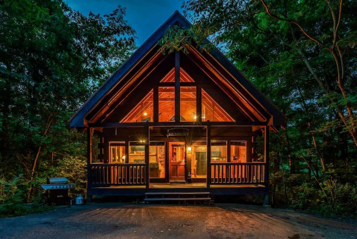 A cabin with a wooden exterior, large windows, and a porch.