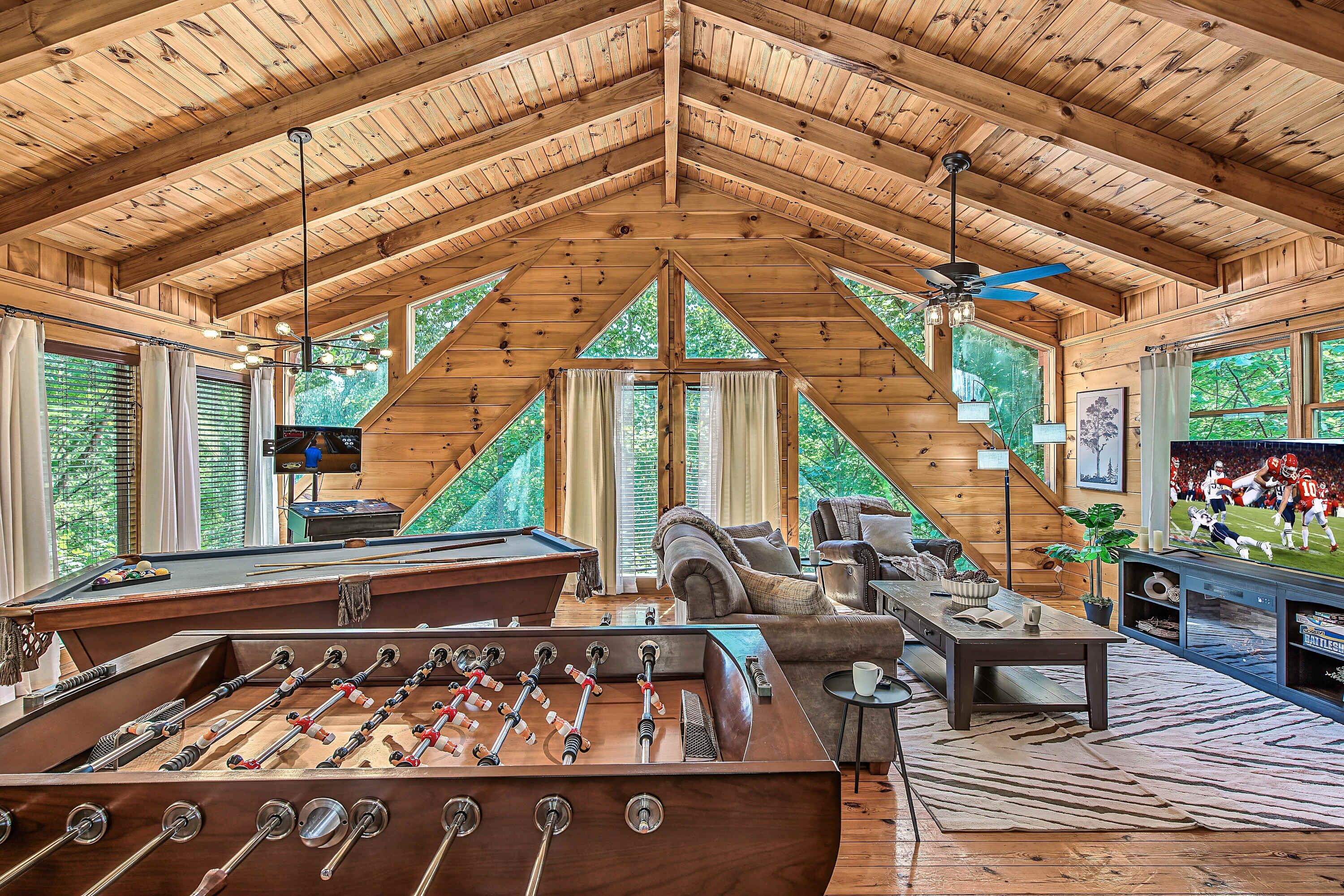 Un loft espacioso con un alto techo de madera, una mesa de fútbol, una mesa de billar y una zona de estar acogedora con chimenea.