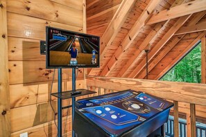 Ein Holzinterieur mit einer Bowlingbahn-Anlage, inklusive einer Kugelfangvorrichtung und einem Monitor, der ein Bowling-Spiel zeigt.